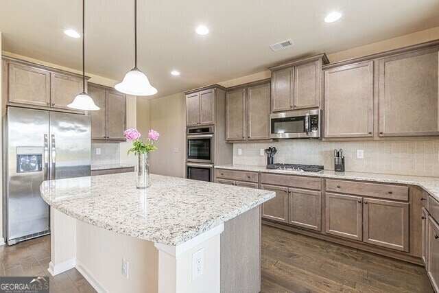 kitchen with light stone countertops, stainless steel appliances, dark hardwood / wood-style floors, backsplash, and pendant lighting