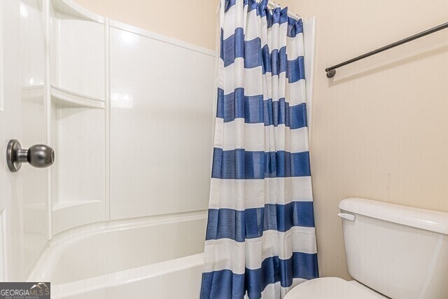 bathroom featuring shower / bath combination with curtain and toilet