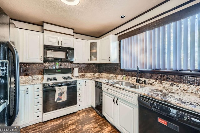 kitchen featuring black appliances, light stone counters, white cabinetry, and sink