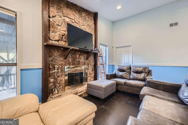 living room with a textured ceiling, dark hardwood / wood-style flooring, a fireplace, and a wealth of natural light