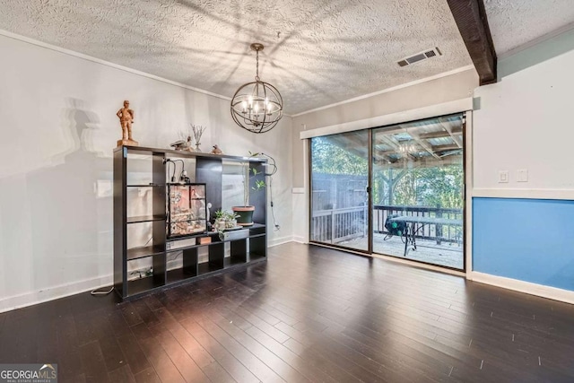 empty room with dark wood-type flooring, ornamental molding, a textured ceiling, beam ceiling, and a chandelier