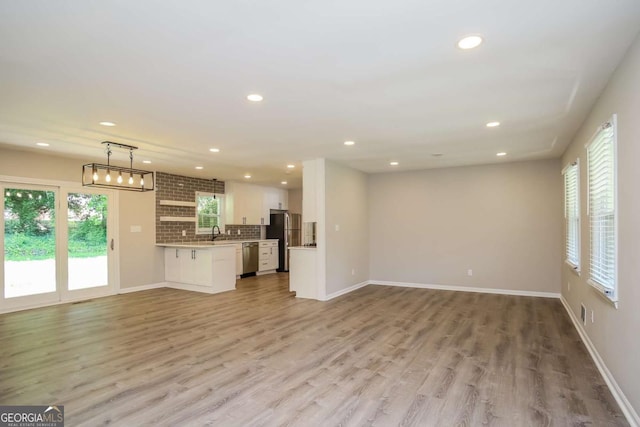 unfurnished living room featuring light wood-type flooring and sink