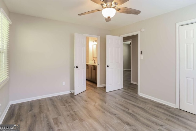 unfurnished bedroom featuring connected bathroom, ceiling fan, and light hardwood / wood-style flooring