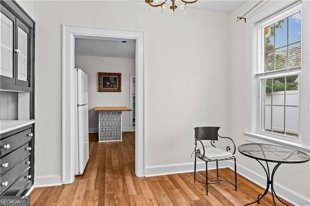 dining area with wood-type flooring, a healthy amount of sunlight, a notable chandelier, and a brick fireplace