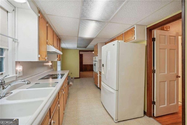 kitchen with wood walls, sink, a drop ceiling, and white appliances