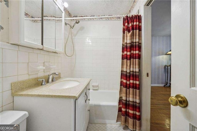 full bathroom with shower / bathtub combination with curtain, wood-type flooring, a textured ceiling, vanity, and tile walls