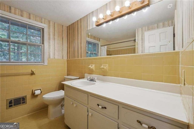 bathroom featuring vanity, curtained shower, toilet, and tile walls