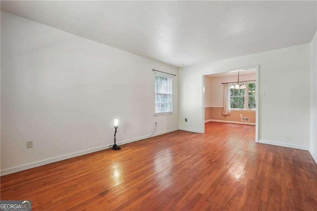 empty room featuring a chandelier and hardwood / wood-style floors