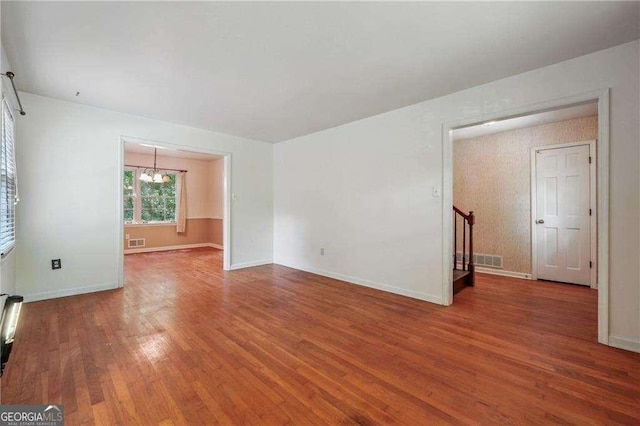 empty room featuring a chandelier and wood-type flooring