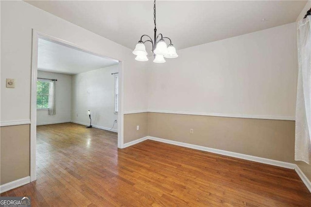 unfurnished room with wood-type flooring and a chandelier