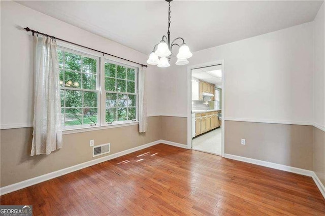 unfurnished room with hardwood / wood-style floors and a chandelier