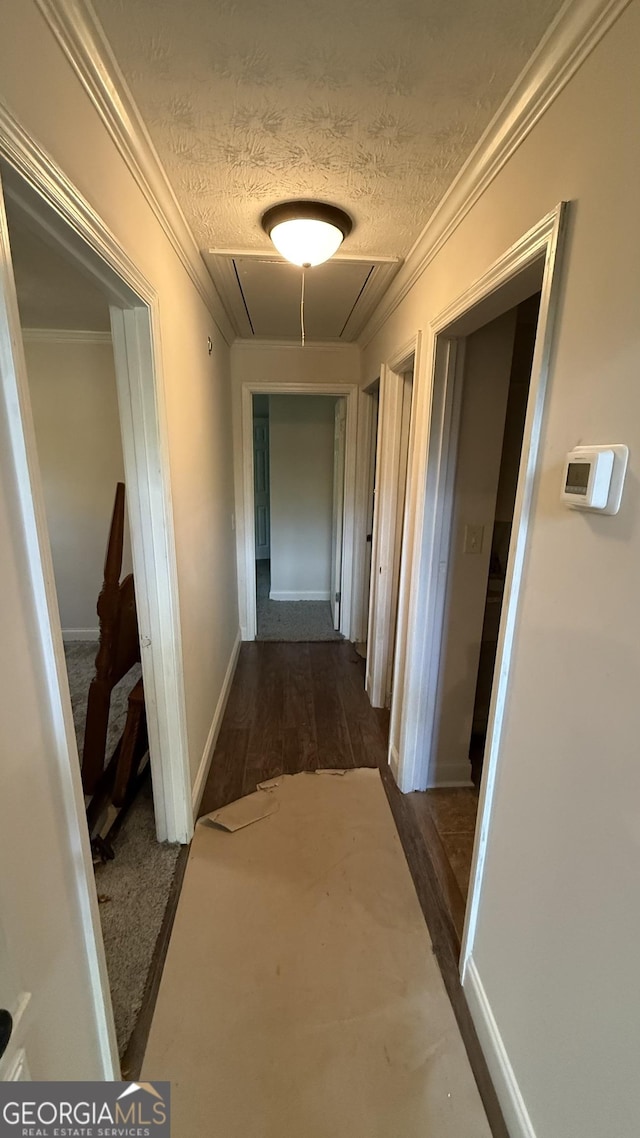 hall with a textured ceiling, crown molding, and dark wood-type flooring