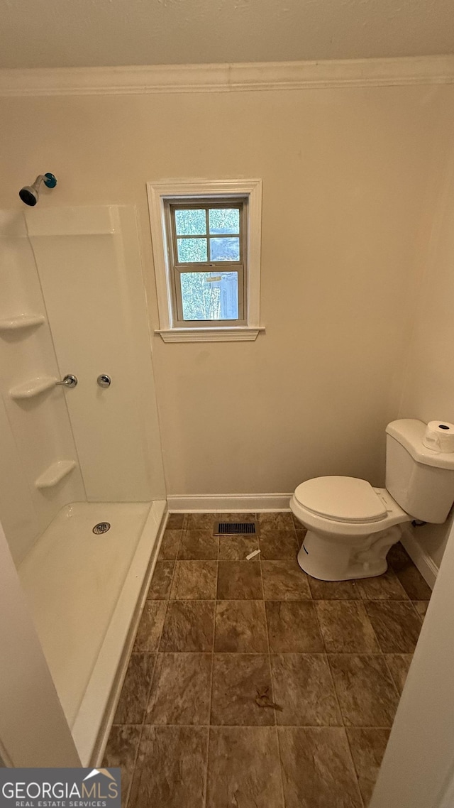 bathroom featuring a shower, crown molding, and toilet