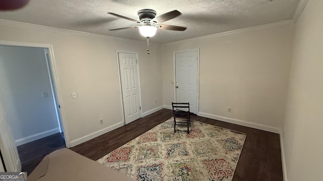 interior space with a textured ceiling, ceiling fan, dark hardwood / wood-style floors, and ornamental molding