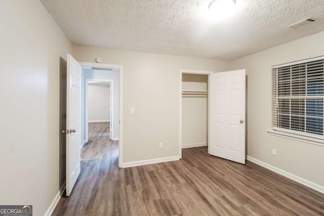 unfurnished bedroom featuring hardwood / wood-style floors, a textured ceiling, and a closet