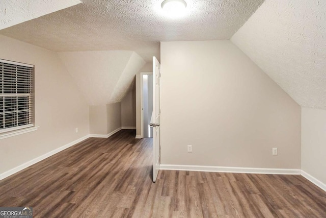 bonus room featuring lofted ceiling, dark hardwood / wood-style flooring, and a textured ceiling