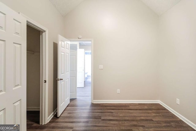 interior space with dark hardwood / wood-style flooring, lofted ceiling, and a textured ceiling