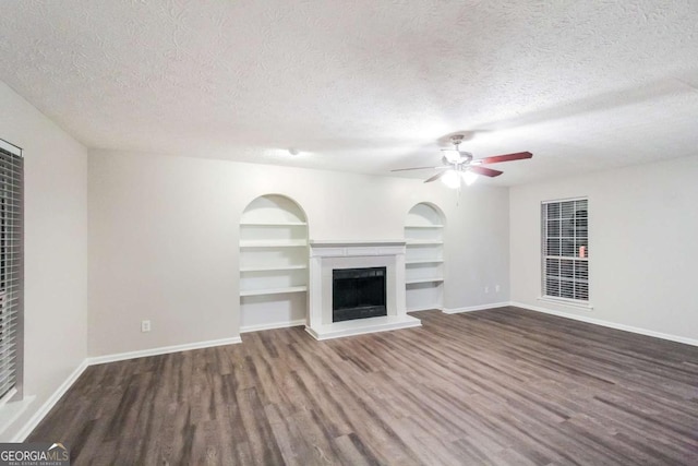 unfurnished living room with a textured ceiling, ceiling fan, and dark hardwood / wood-style floors