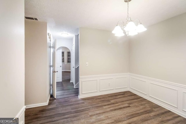 unfurnished dining area featuring a chandelier, dark wood-type flooring, and a textured ceiling