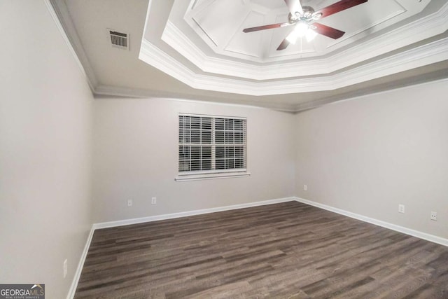 empty room with dark wood-type flooring, a raised ceiling, and ornamental molding