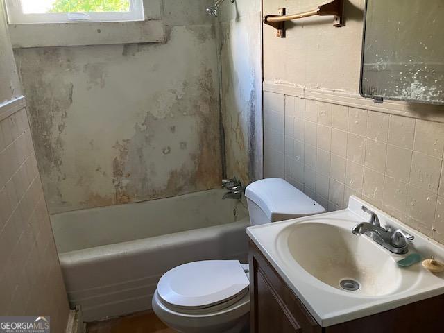 full bathroom featuring shower / bathing tub combination, vanity, tile walls, and toilet