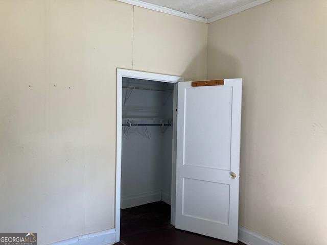 unfurnished bedroom featuring crown molding and a closet