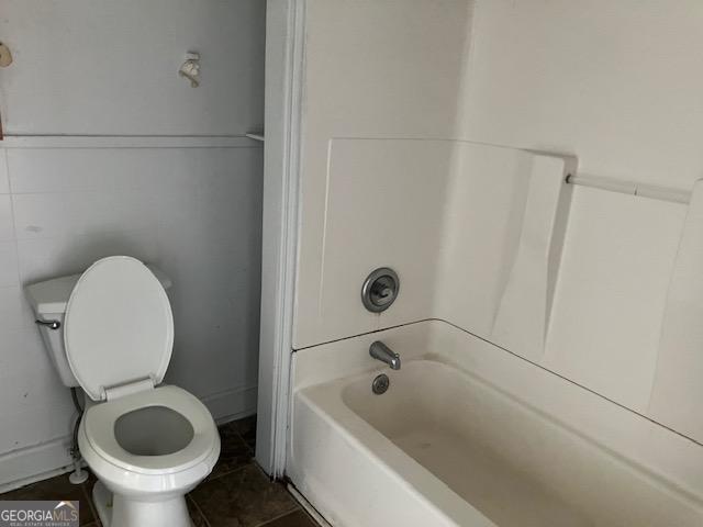 bathroom featuring toilet, bathing tub / shower combination, and tile patterned floors