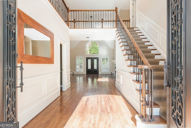 foyer entrance featuring hardwood / wood-style flooring, a towering ceiling, and french doors