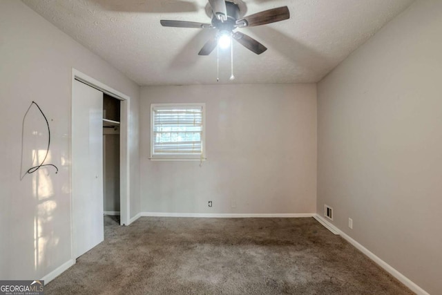 unfurnished bedroom with carpet flooring, ceiling fan, a textured ceiling, and a closet