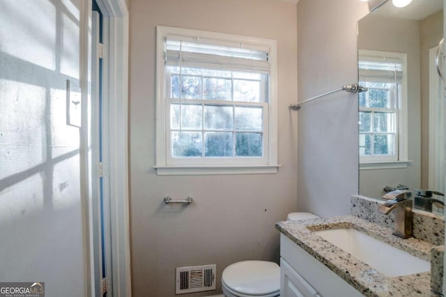 bathroom with vanity, toilet, and a wealth of natural light