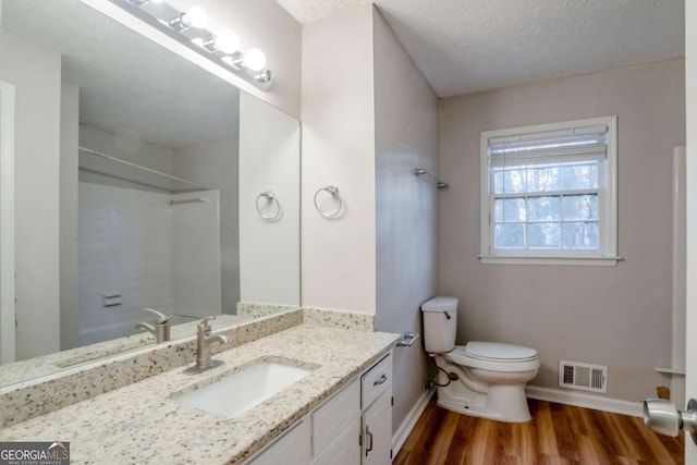 full bathroom featuring hardwood / wood-style floors, vanity, toilet, a textured ceiling, and shower / bathtub combination