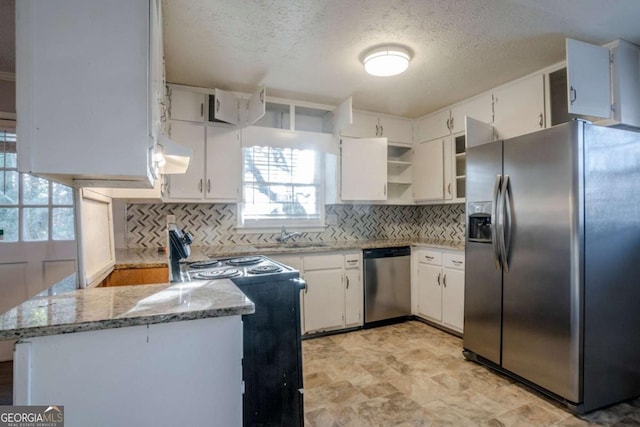 kitchen with sink, kitchen peninsula, light stone counters, white cabinetry, and stainless steel appliances