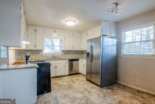 kitchen with tasteful backsplash, plenty of natural light, white cabinets, and stainless steel appliances