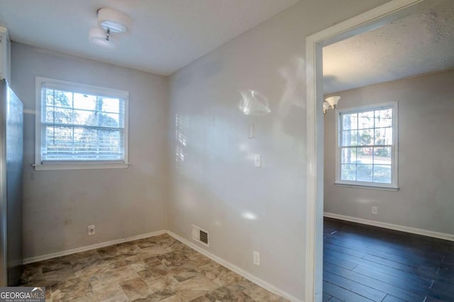 spare room with hardwood / wood-style floors, an inviting chandelier, and a wealth of natural light