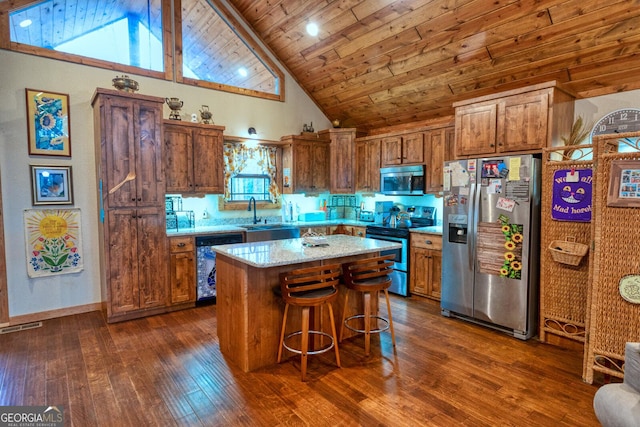 kitchen with dark hardwood / wood-style flooring, light stone counters, stainless steel appliances, wooden ceiling, and a kitchen island