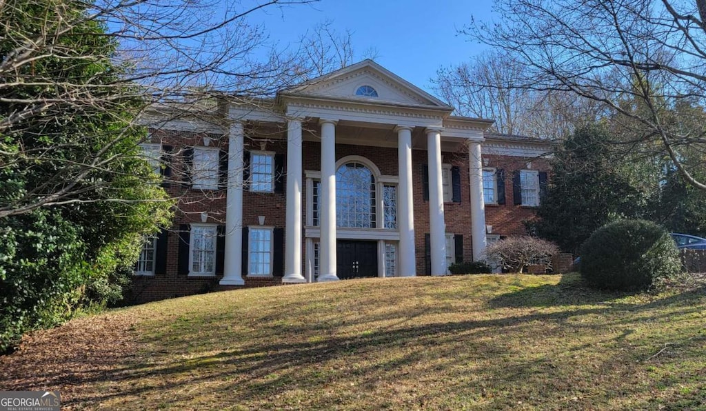 neoclassical home featuring a garage and a front lawn