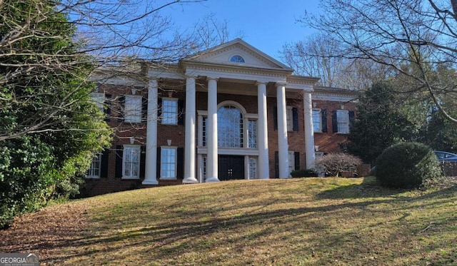 neoclassical home featuring a garage and a front lawn