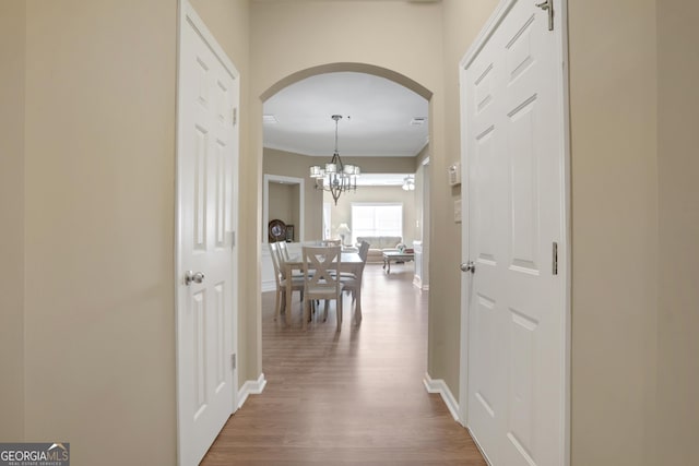 hall featuring hardwood / wood-style floors, a chandelier, and ornamental molding