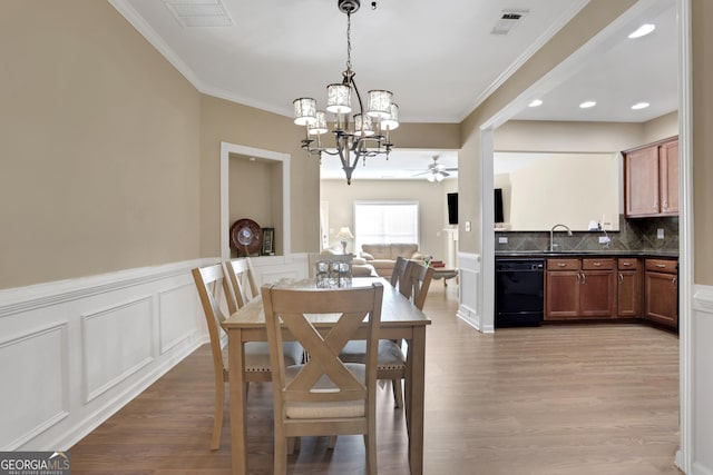 dining area featuring ceiling fan with notable chandelier, light wood-type flooring, and crown molding