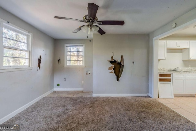 carpeted spare room featuring ceiling fan and sink