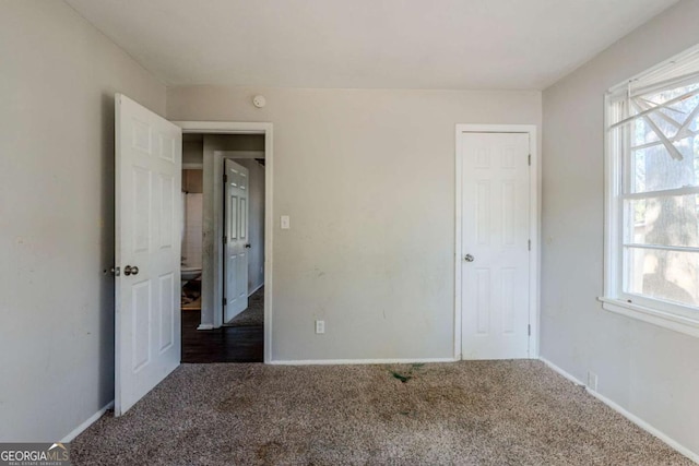 unfurnished bedroom with dark colored carpet and multiple windows