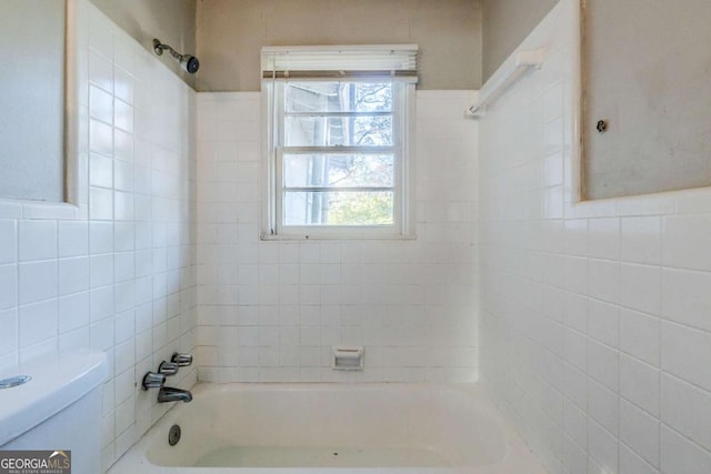 bathroom featuring toilet and tiled shower / bath