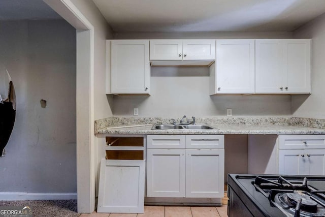 kitchen featuring sink, white cabinets, stove, and light tile patterned floors