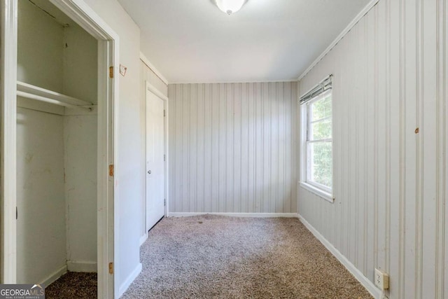 unfurnished bedroom featuring carpet, crown molding, and a closet