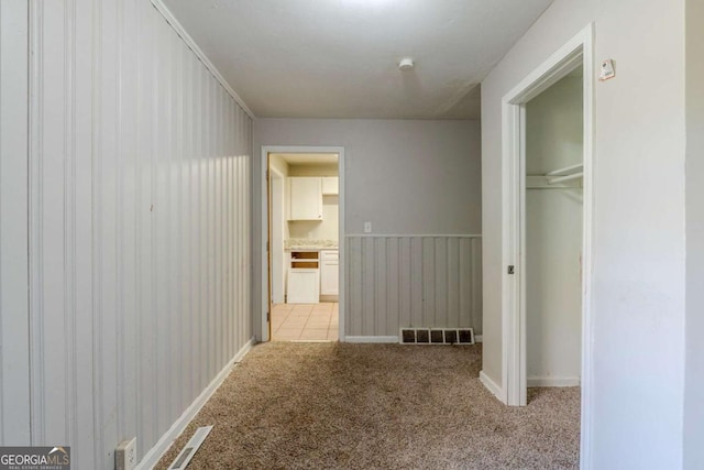 hall featuring light carpet and wooden walls