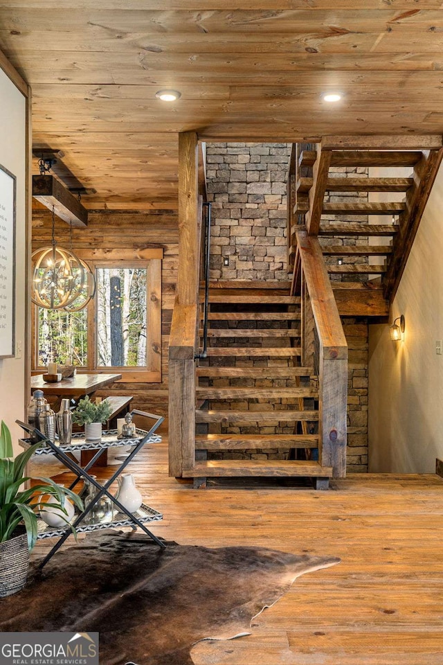 stairs featuring hardwood / wood-style floors, a notable chandelier, and wood ceiling