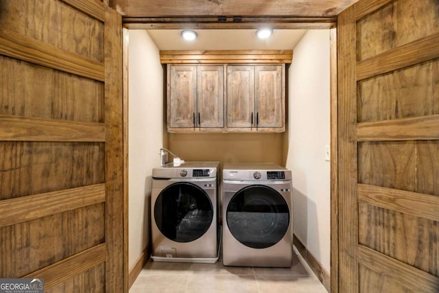 laundry area featuring independent washer and dryer, cabinets, and light tile patterned floors