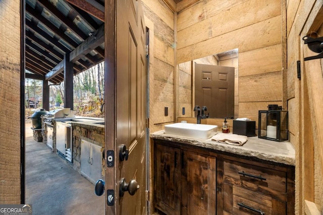 bathroom featuring wooden walls, vanity, concrete flooring, and lofted ceiling