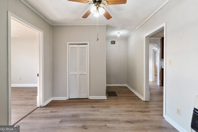 unfurnished bedroom featuring ceiling fan, ornamental molding, a textured ceiling, and light hardwood / wood-style flooring