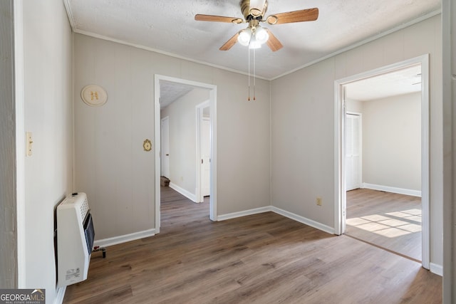 spare room with hardwood / wood-style flooring, ceiling fan, ornamental molding, and heating unit